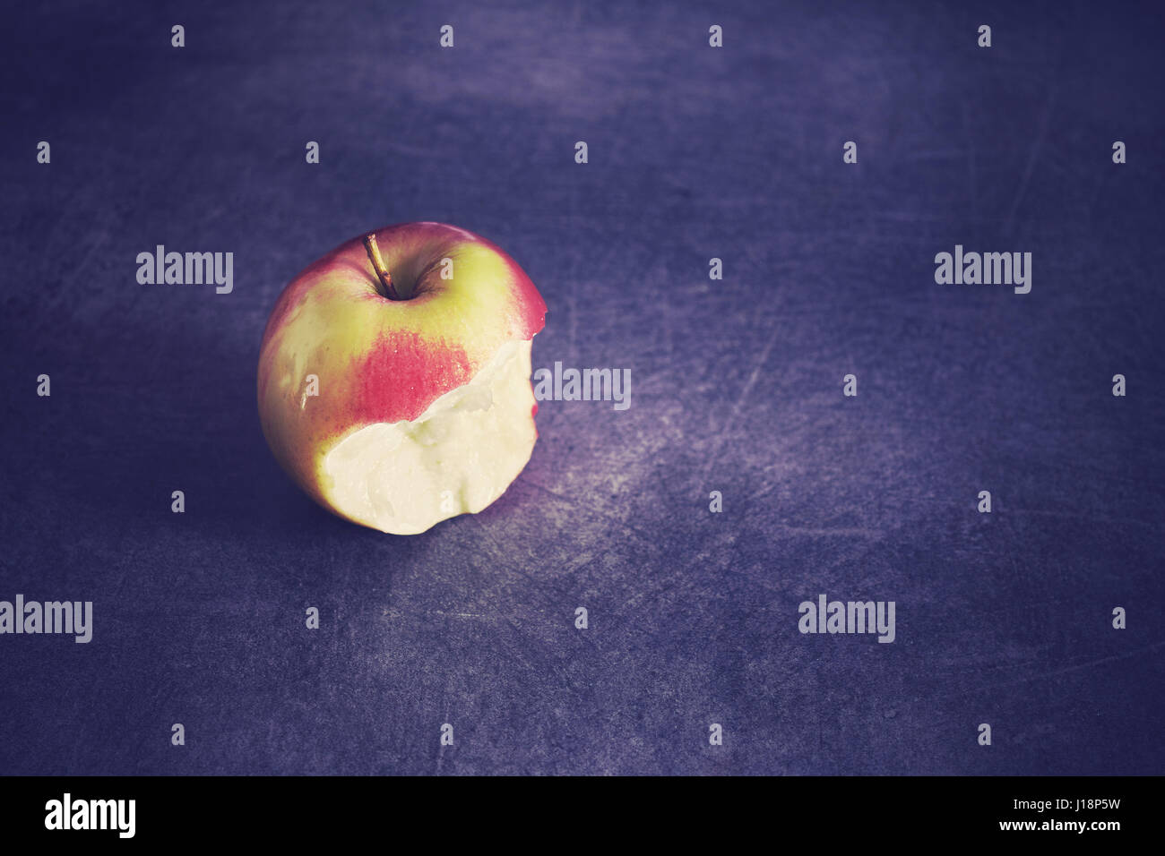Color toned ripe bitten apple on a dark background, selective focus, space for text. Stock Photo