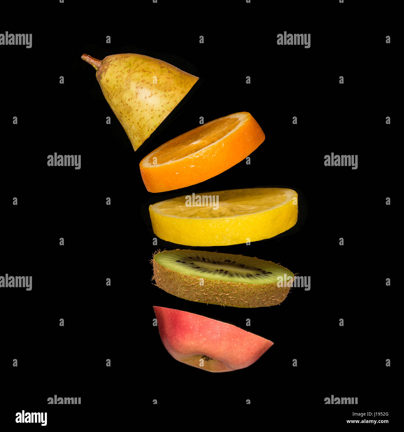 Surrealistic creative concept with flying fruit. Pieces of pear, orange, lemon, kiwi and apple on a black background Stock Photo
