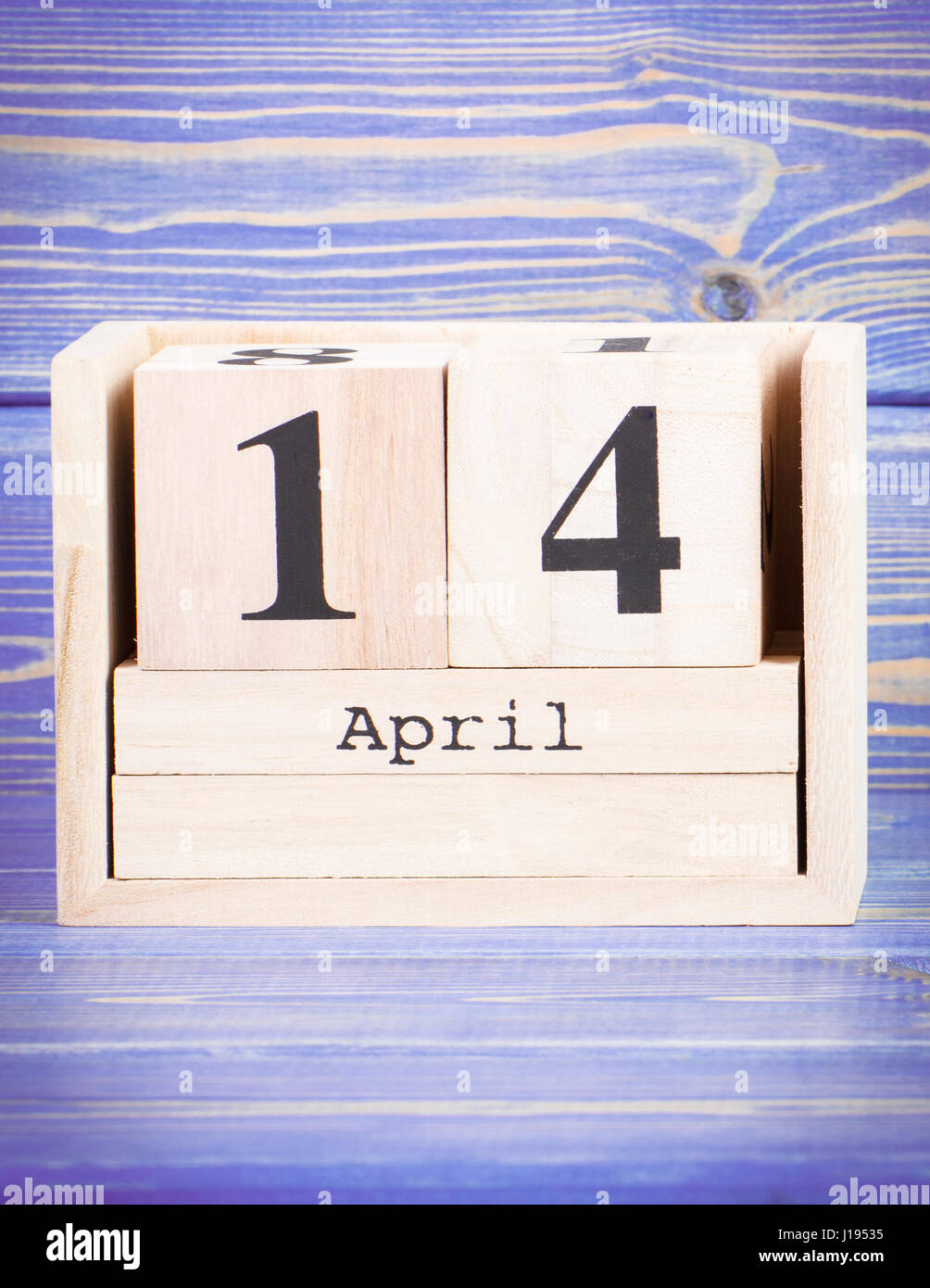 April 14th. Date of 14 April on wooden cube calendar, purple board as