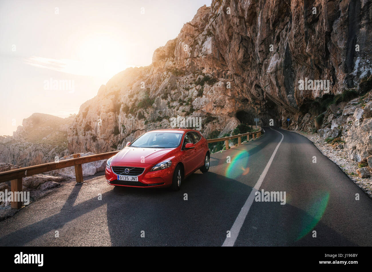 Red car Volvo V40 traveling on the mountain serpentine through a tunnel of a rock along the coast of Majorca Stock Photo