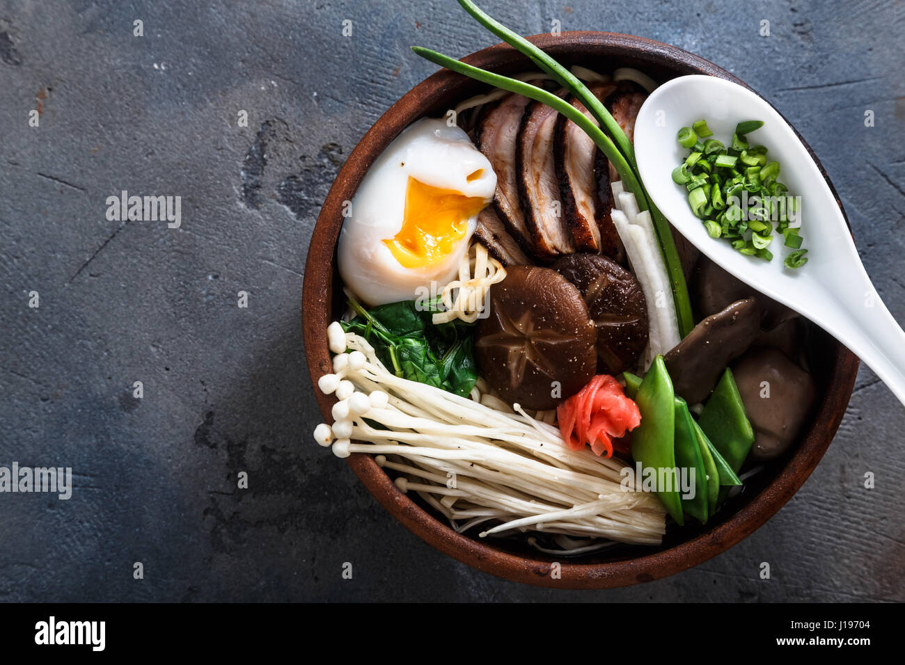 Duck noodles with egg and mushrooms in bowl on dark black stone texture background Stock Photo
