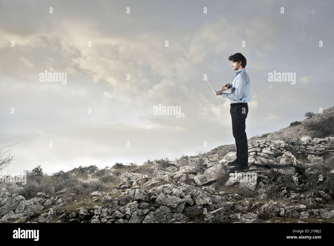 Businessman on mountain with laptop Stock Photo