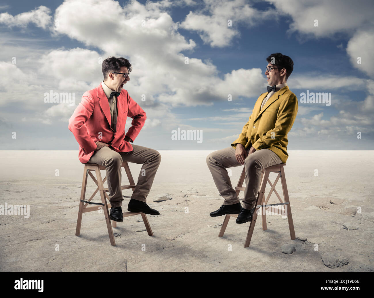 2 men sitting in front of each other in desert Stock Photo
