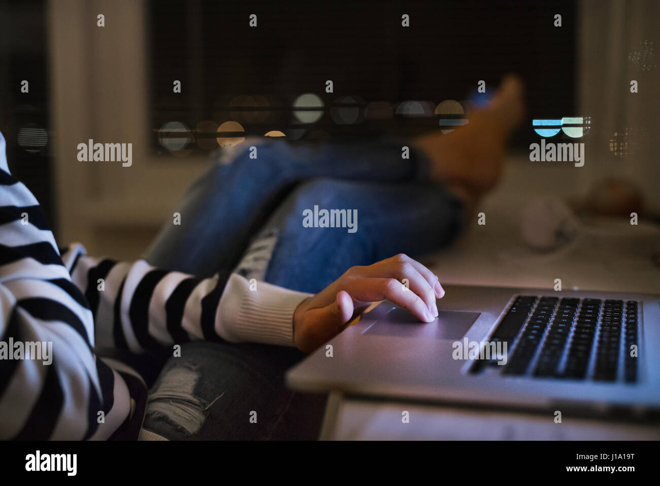 Unrecognizable woman sitting at desk at night working on laptop late at ...