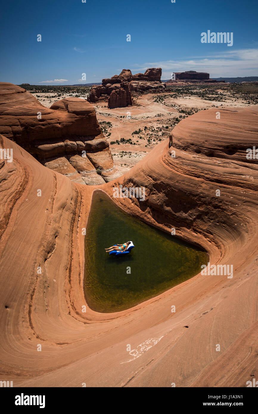 Natali Zollinger relaxing in a pool lounger in a natural pothole pool near Moab, Utah. Stock Photo
