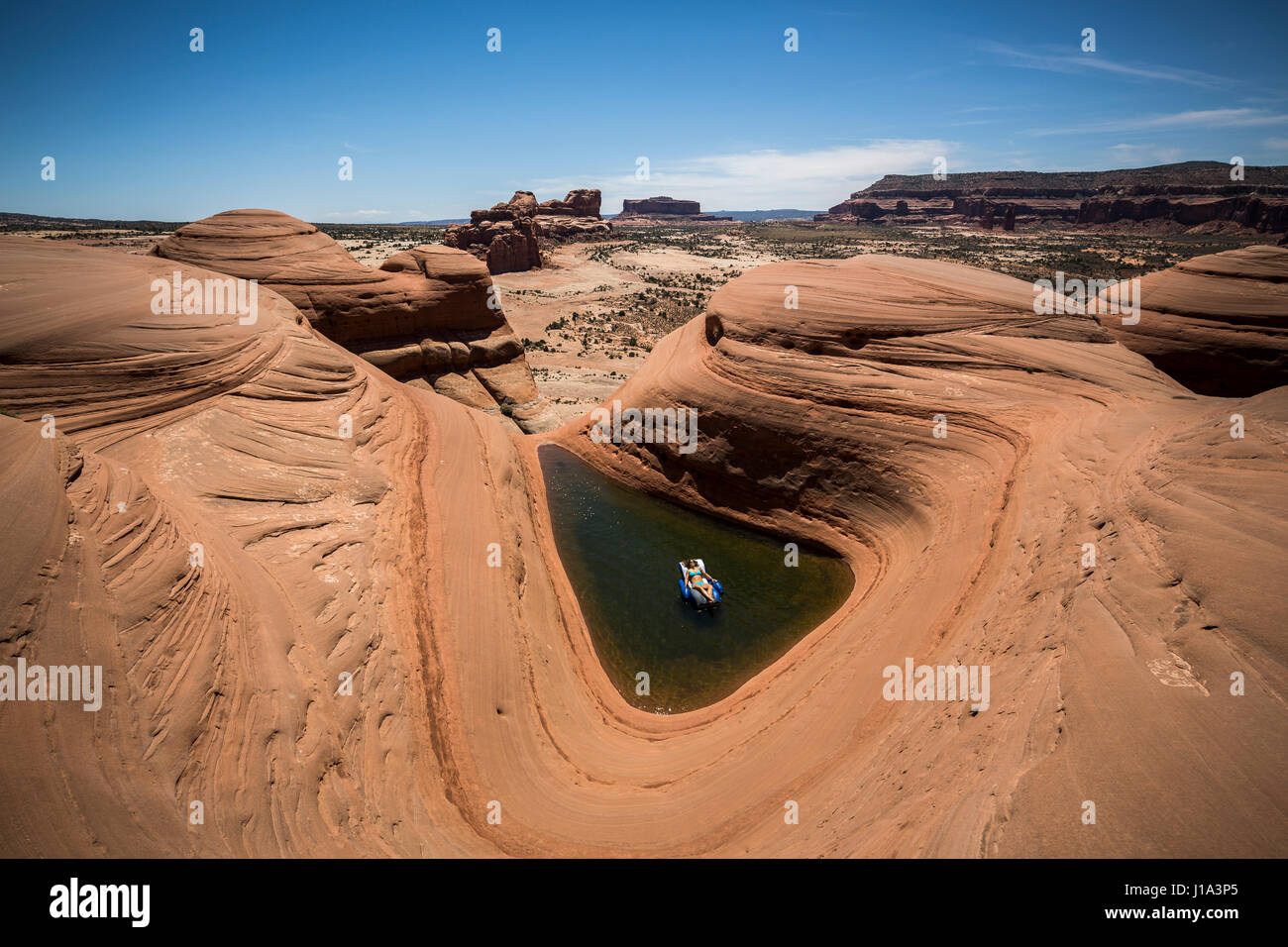 Natali Zollinger relaxing in a pool lounger in a natural pothole pool near Moab, Utah. Stock Photo