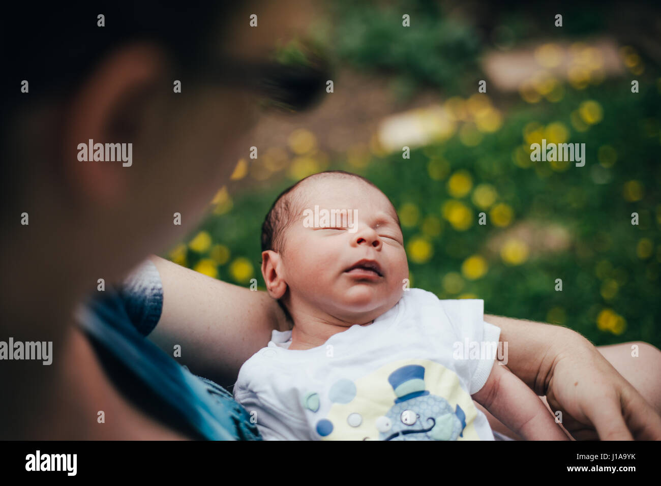 Newborn sleeps in his mothers arms outside in the garden Stock Photo