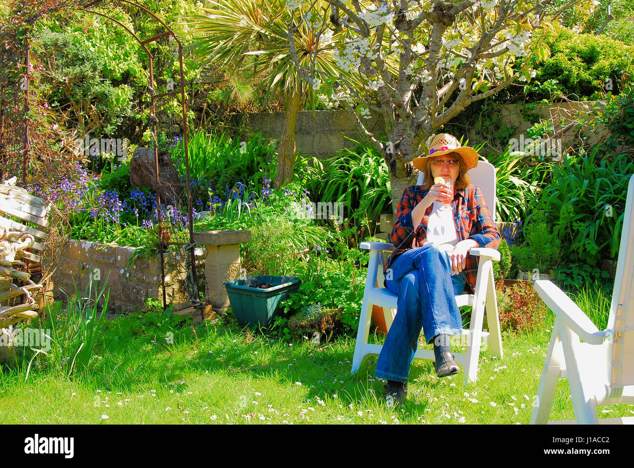Portland, UK. 19th Apr, 2017. A woman relaxes in a sunny Portland garden, savouring her first summer punch of the year Credit: stuart fretwell/Alamy Live News Stock Photo