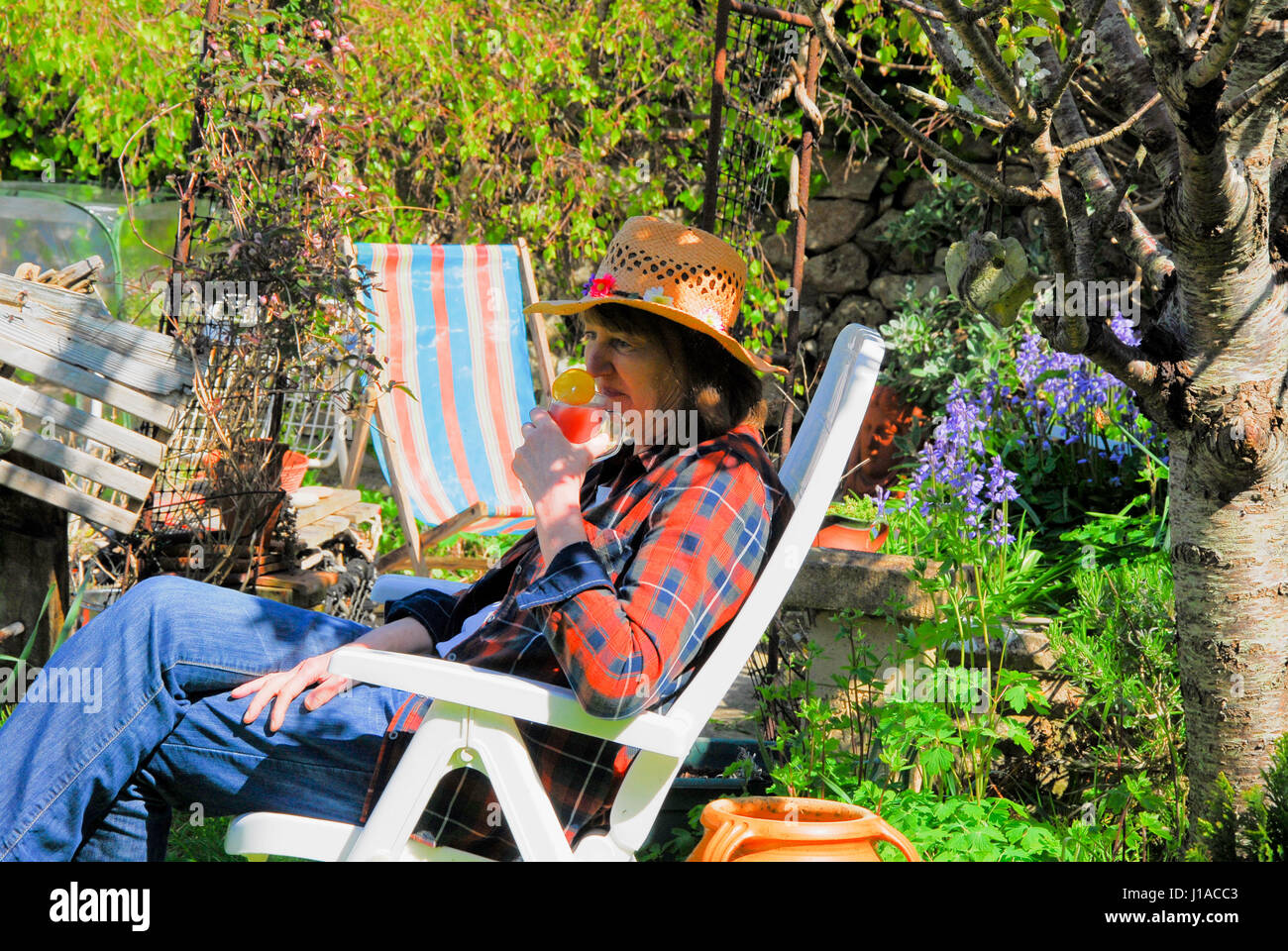 Portland, UK. 19th Apr, 2017. A woman relaxes in a sunny Portland garden, savouring her first summer punch of the year Credit: stuart fretwell/Alamy Live News Stock Photo