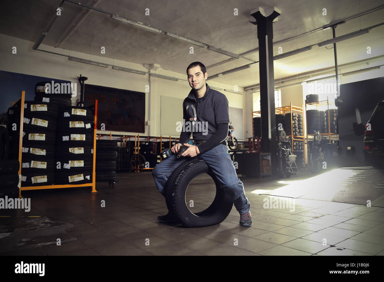 Mechanic man sitting on tire Stock Photo