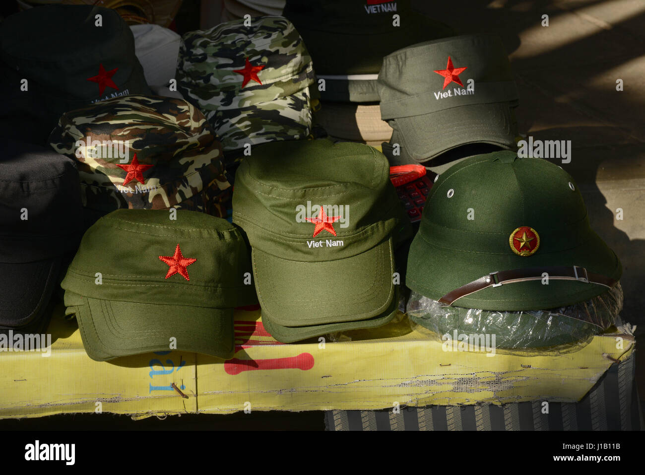 Souvenir Viet Cong caps for sale to tourists on a market stall in the town of Hoi An, in Quang Nam Province, Vietnam. Stock Photo