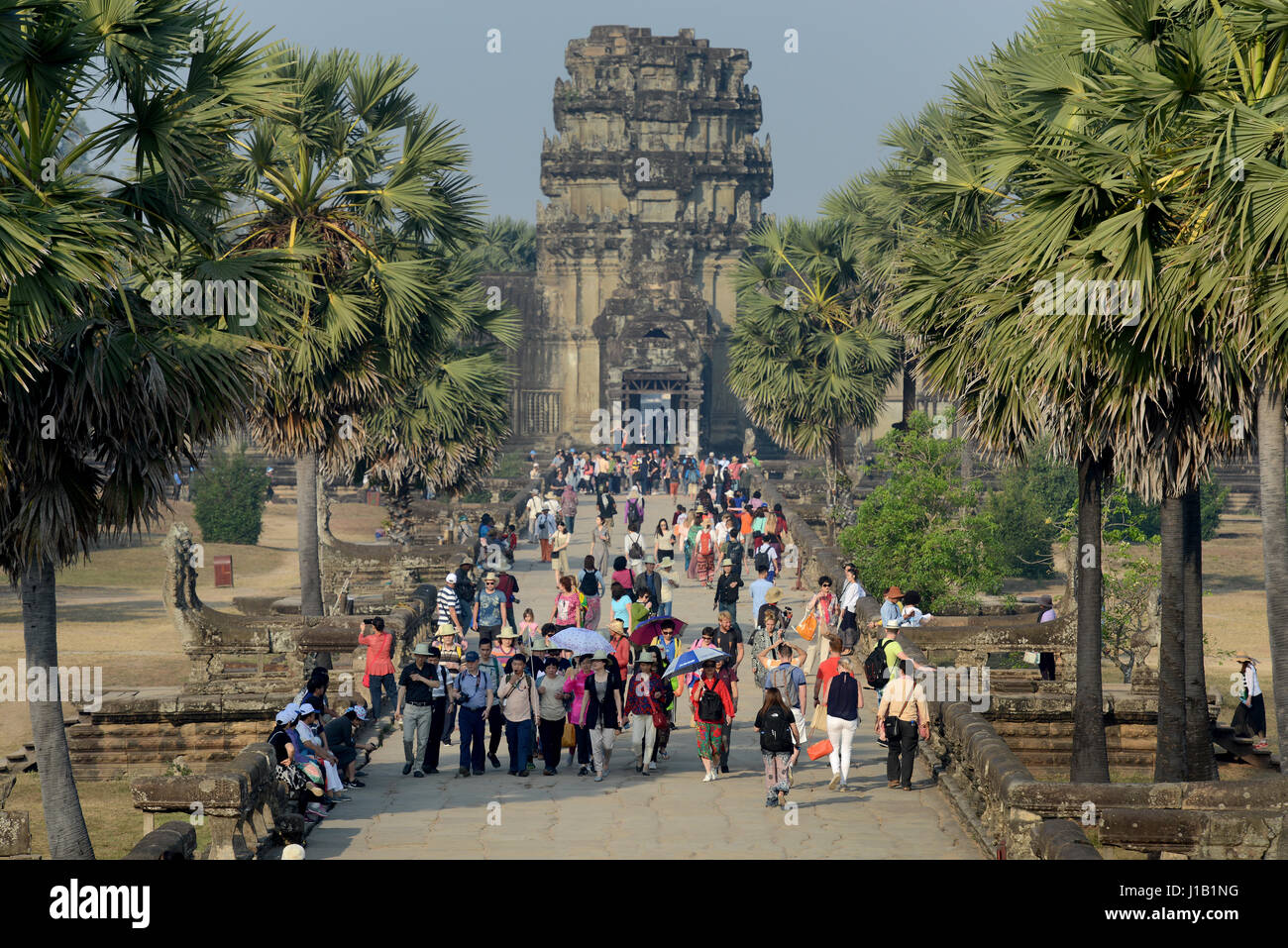 Tourists arriving to visit the religious monument of Angkor Wat by way of the causeway, in Siem Reap, Cambodia. Stock Photo