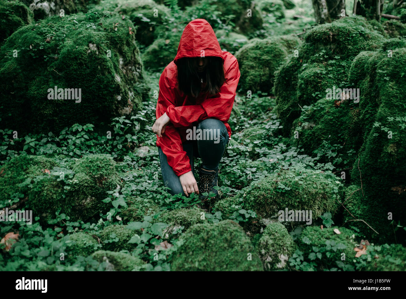 Caucasian woman kneeling in lush forest Stock Photo