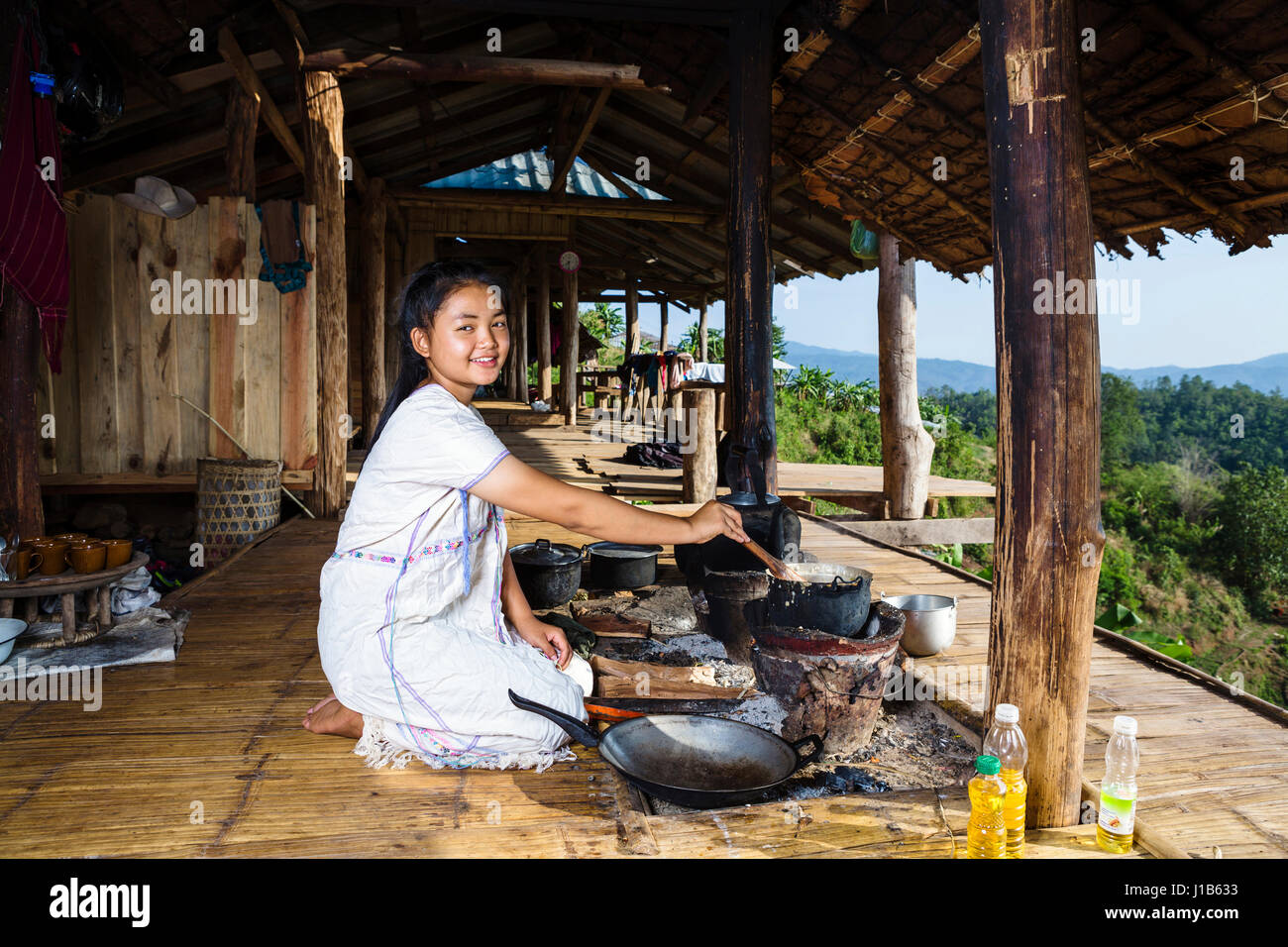 Smiling Asian woman cooking on patio outdoors Stock Photo