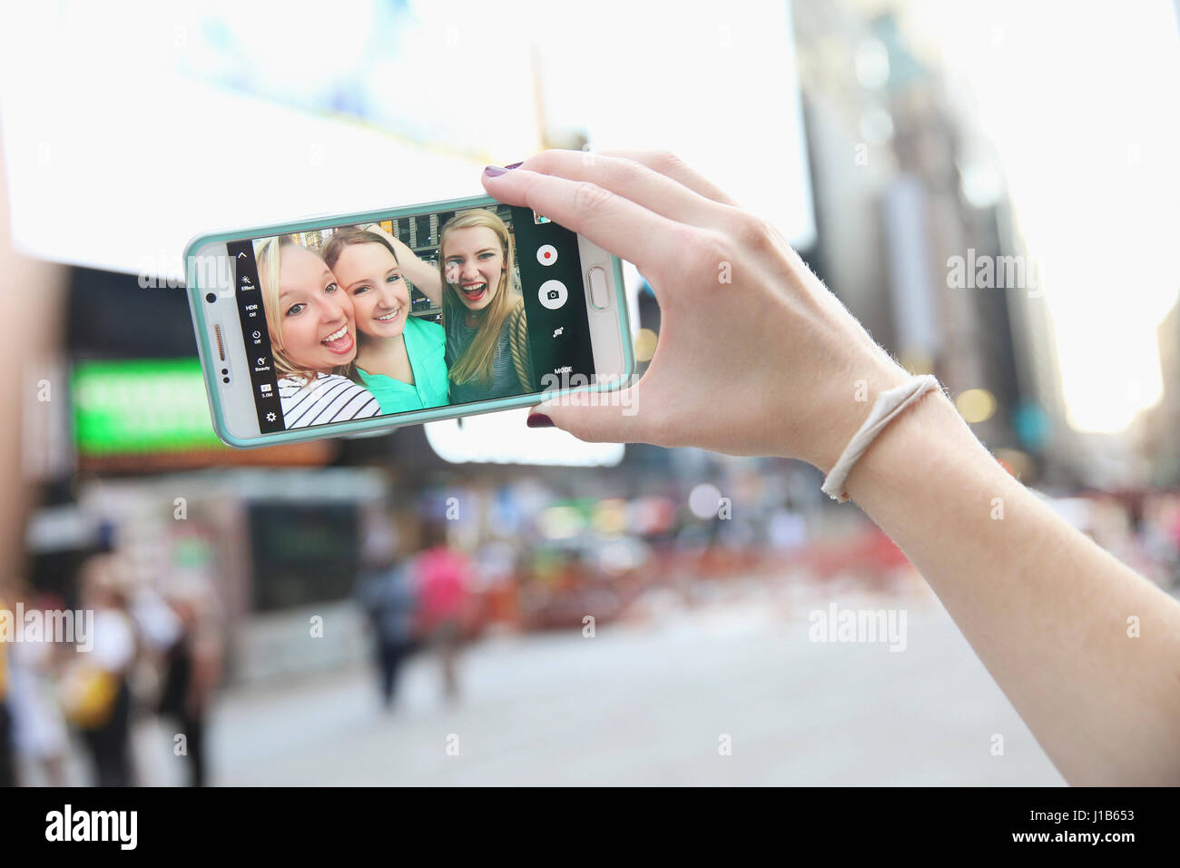 Arm of Caucasian woman posing for cell phone selfie with friends Stock Photo