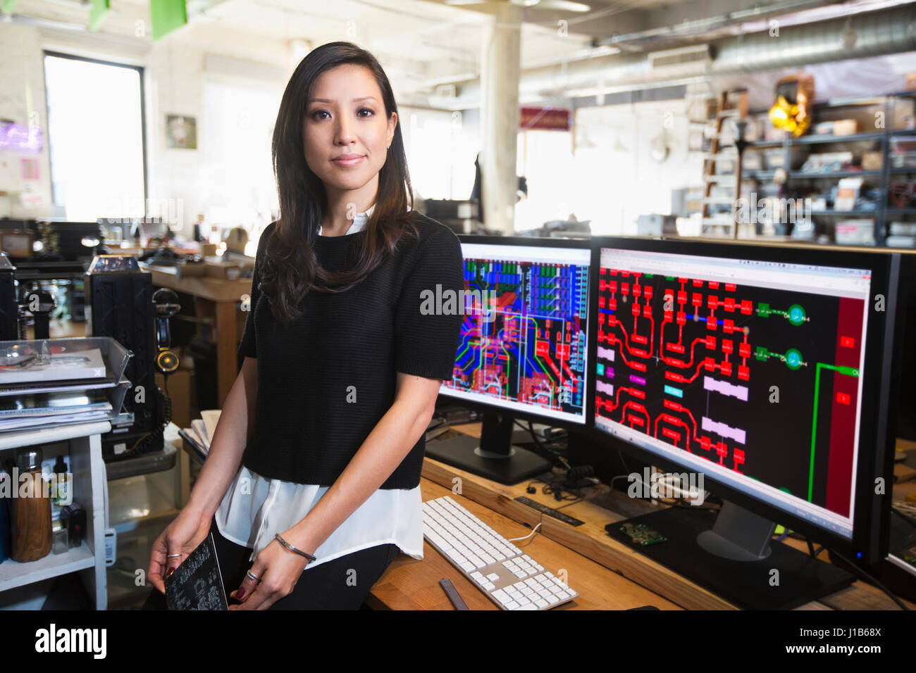 Mixed Race woman posing near circuits on computer monitors Stock Photo