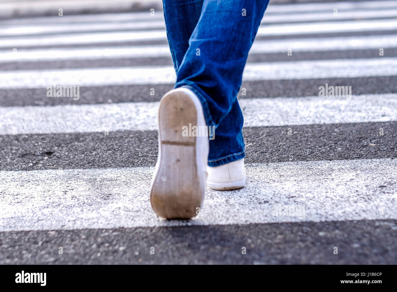 Legs of African American woman walking in crosswalk Stock Photo