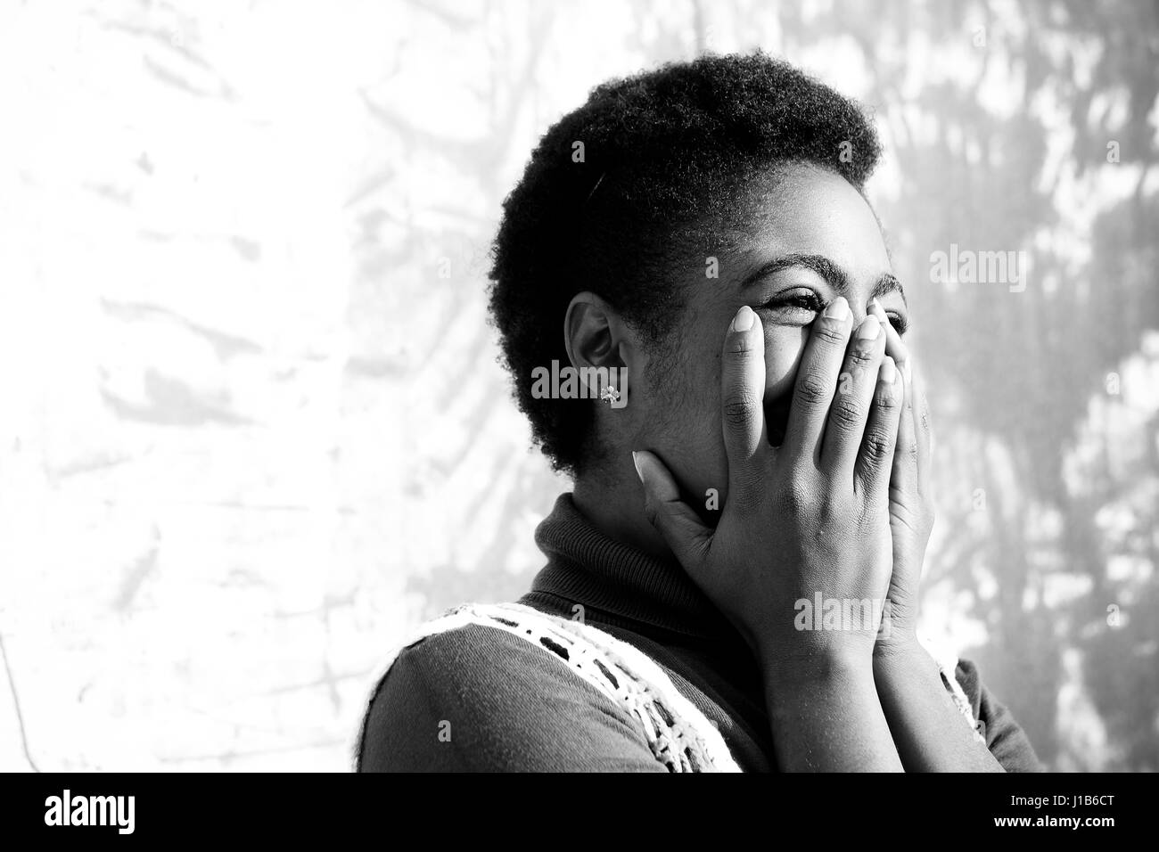 Laughing African American woman with hands on face Stock Photo