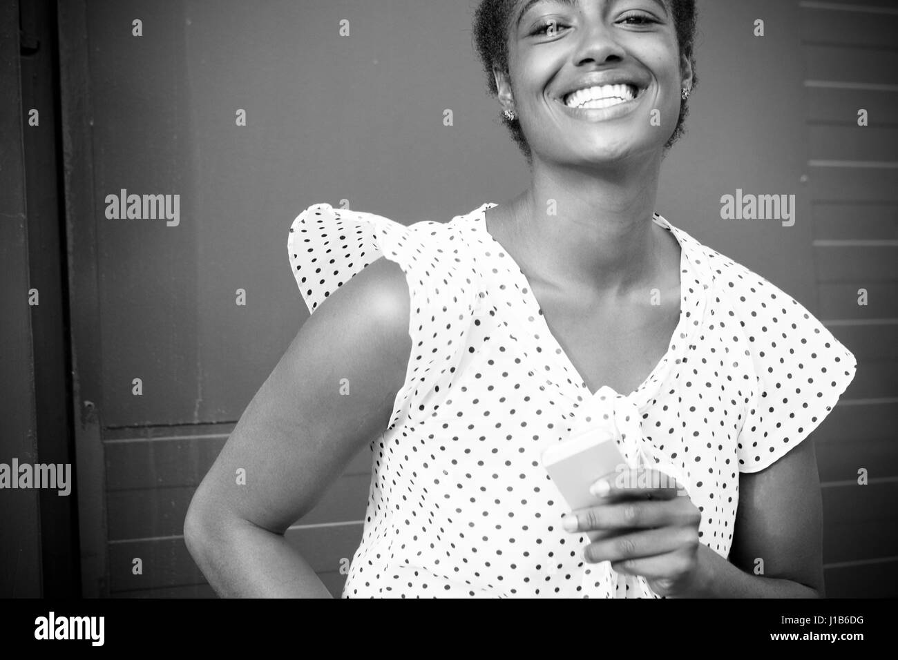 Smiling African American woman holding cell phone Stock Photo