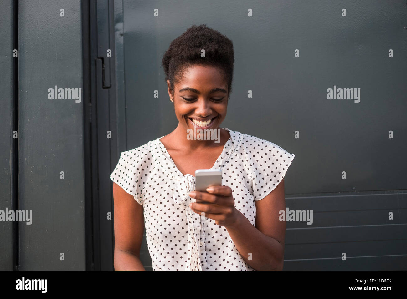 Smiling African American woman texting on cell phone Stock Photo
