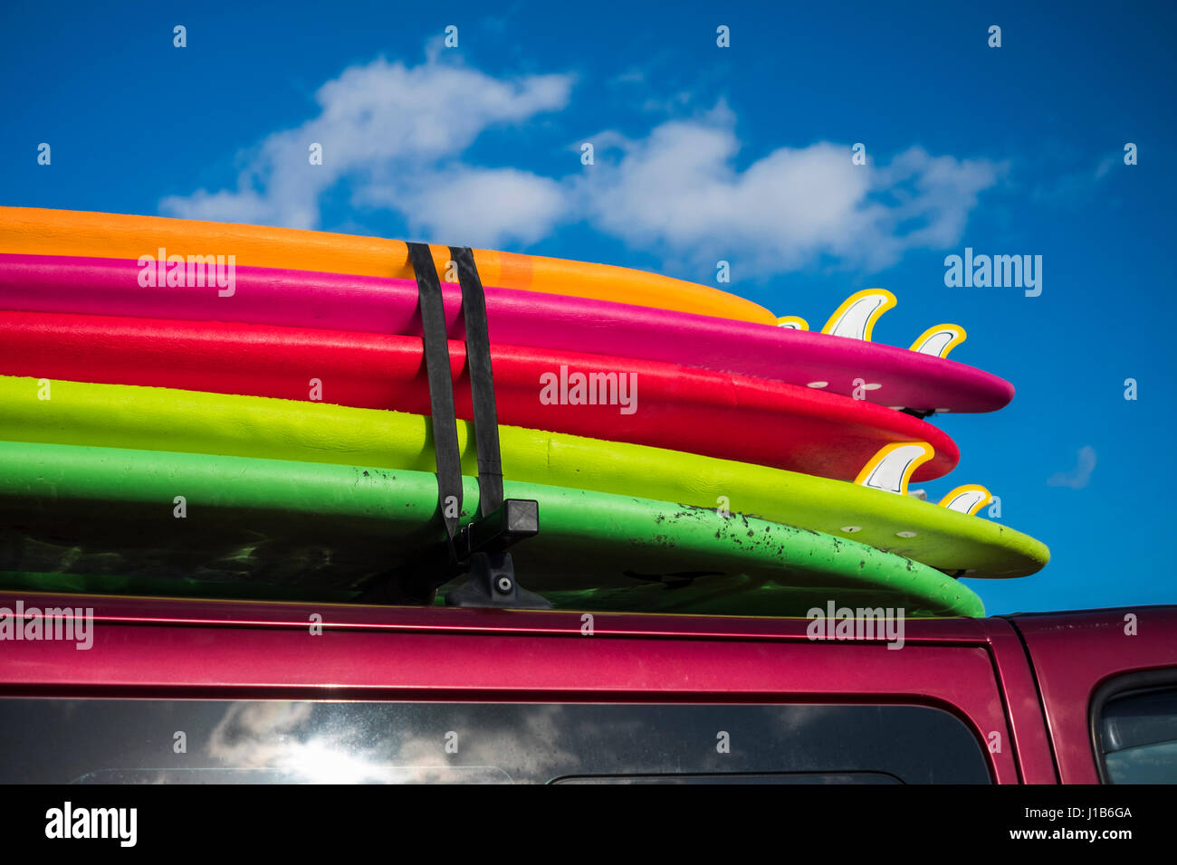 Multicolor surfboards strapped to roof of car Stock Photo