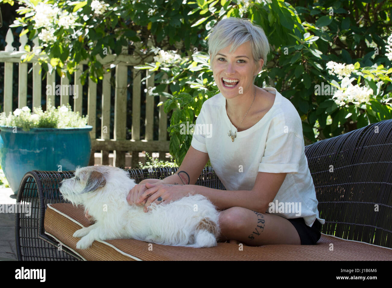 Smiling Caucasian woman petting dog on sofa outdoors Stock Photo