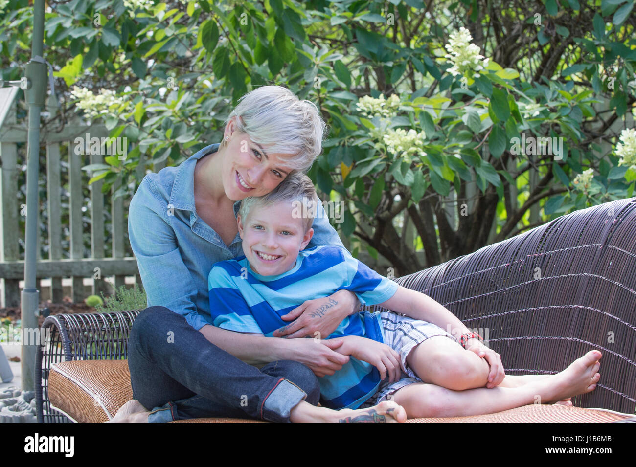 Caucasian woman hugging son on sofa outdoors Stock Photo