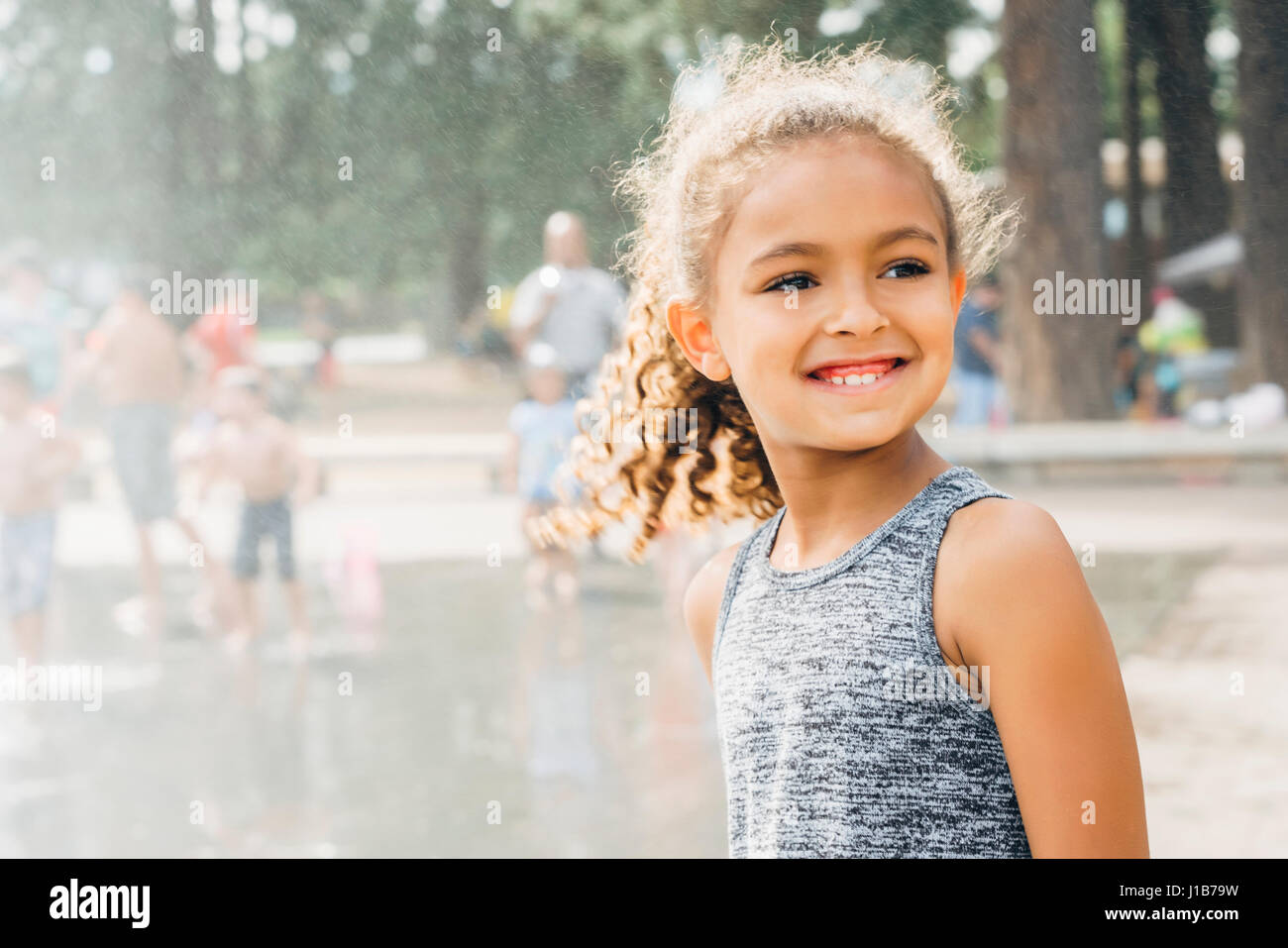 Mixed Race girl smiling in park near fountain Stock Photo