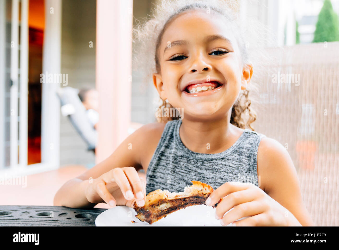 Smiling Mixed Race girl eating rib outdoors Stock Photo