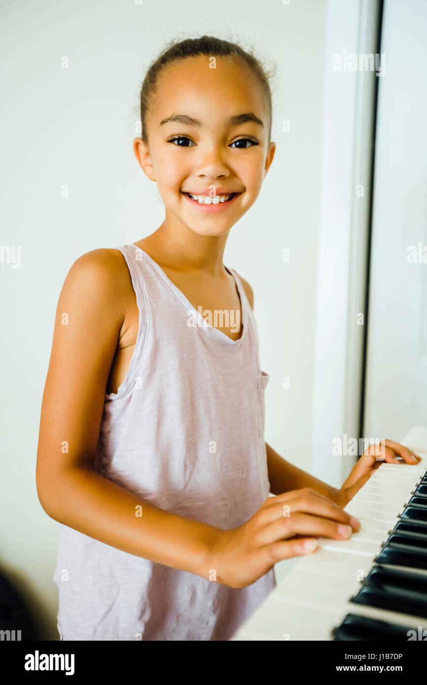 Smiling Mixed Race girl playing music on keyboard Stock Photo