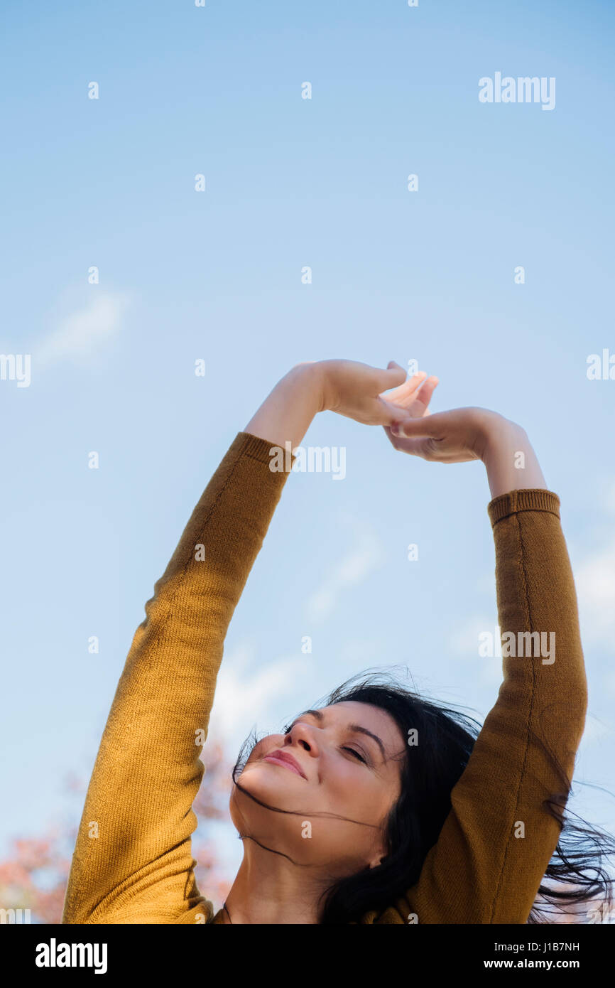 Wind blowing hair of Caucasian woman with arms raised Stock Photo