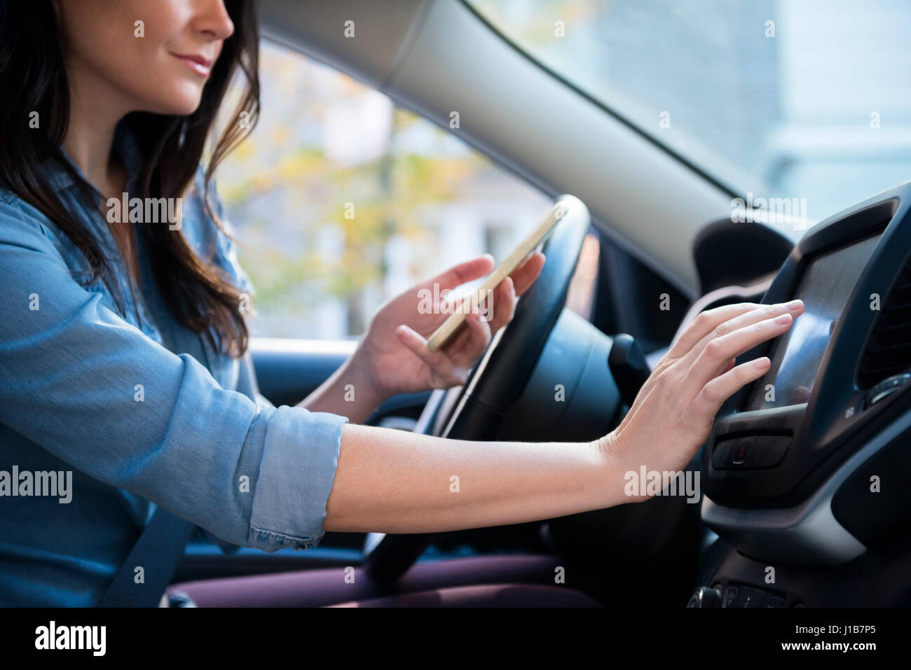 Caucasian woman in car holding cell phone programming journey Stock Photo