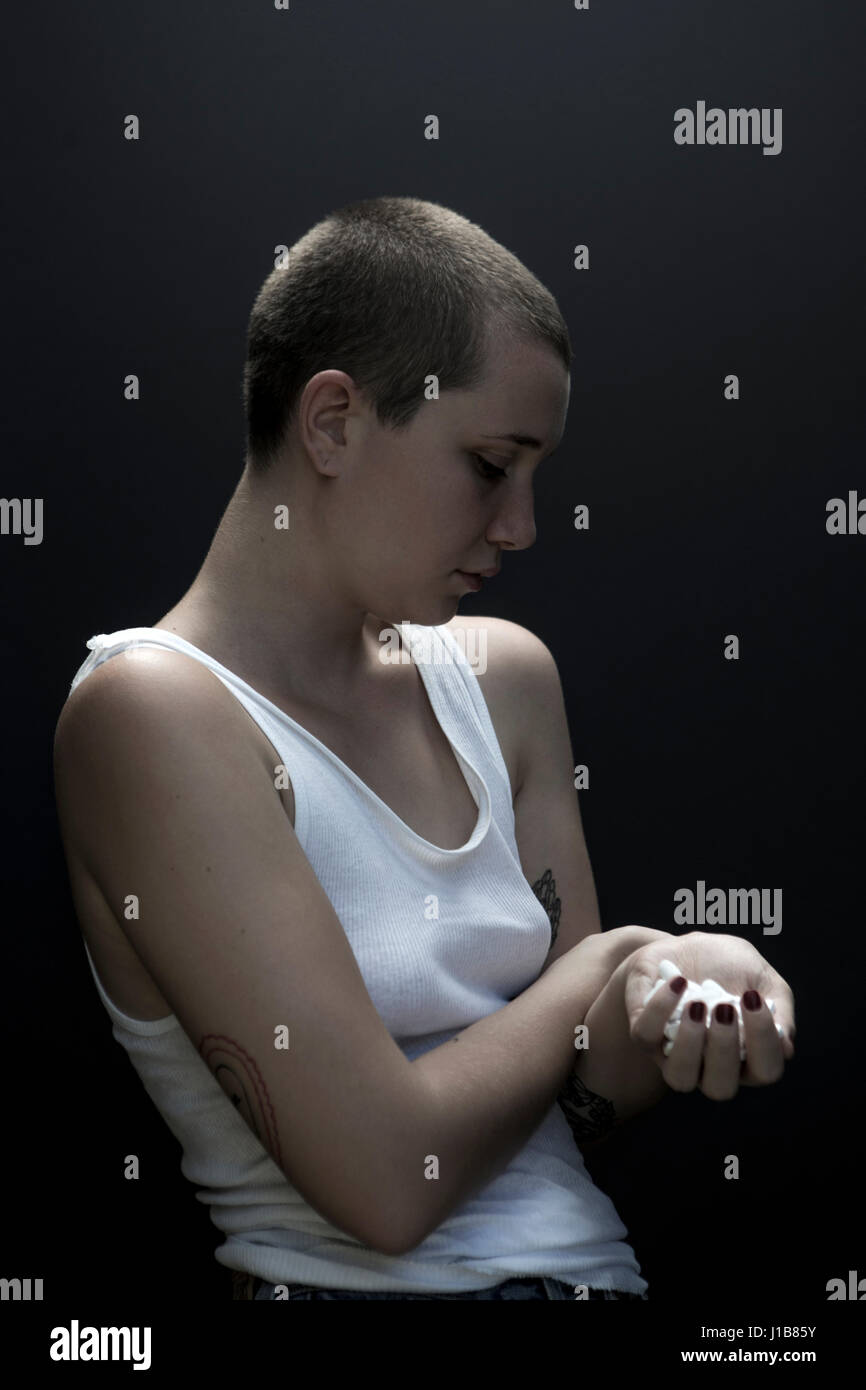 Serious Caucasian woman with shaved-head holding pills Stock Photo