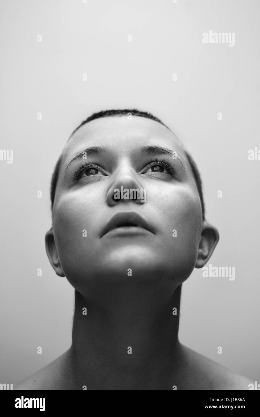 Caucasian woman with shaved-head looking up Stock Photo