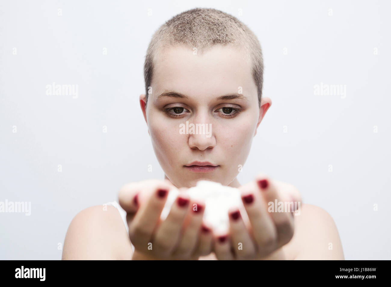 Serious Caucasian woman with shaved-head holding pills Stock Photo