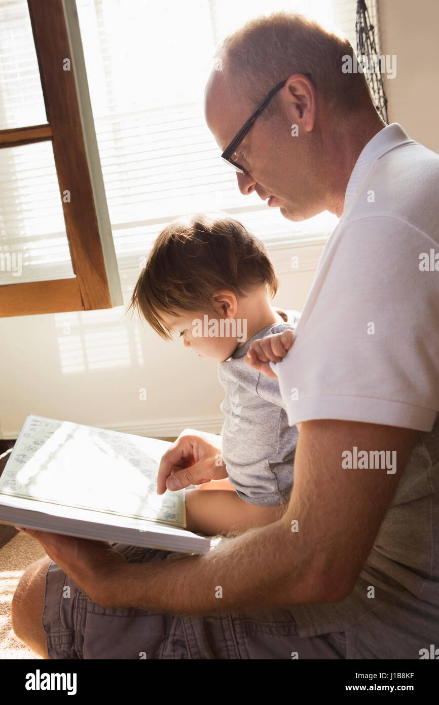 Father reading book to son in lap Stock Photo
