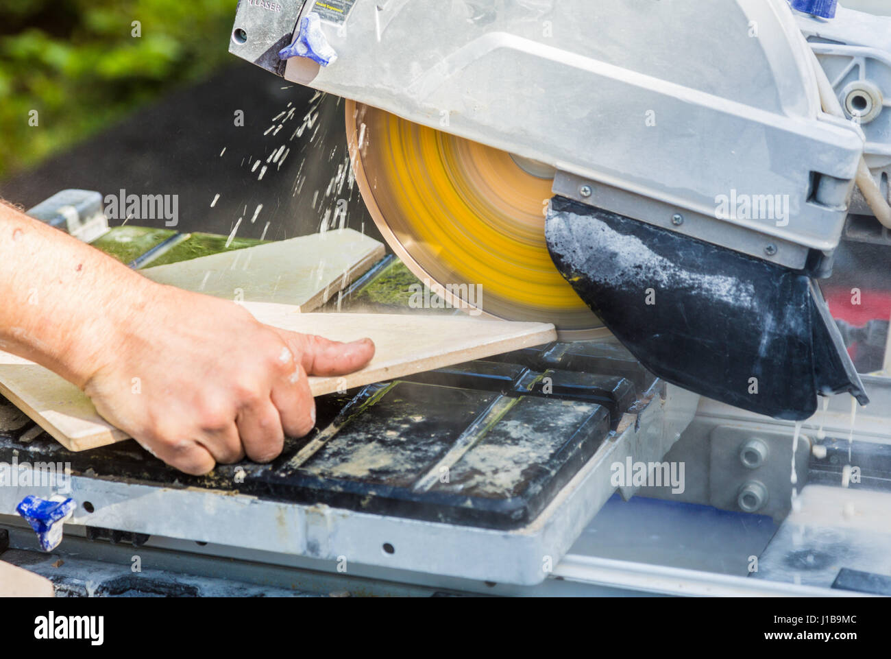 Using a diamond tipped blade circular saw cutting through a ceramic floor tile Stock Photo