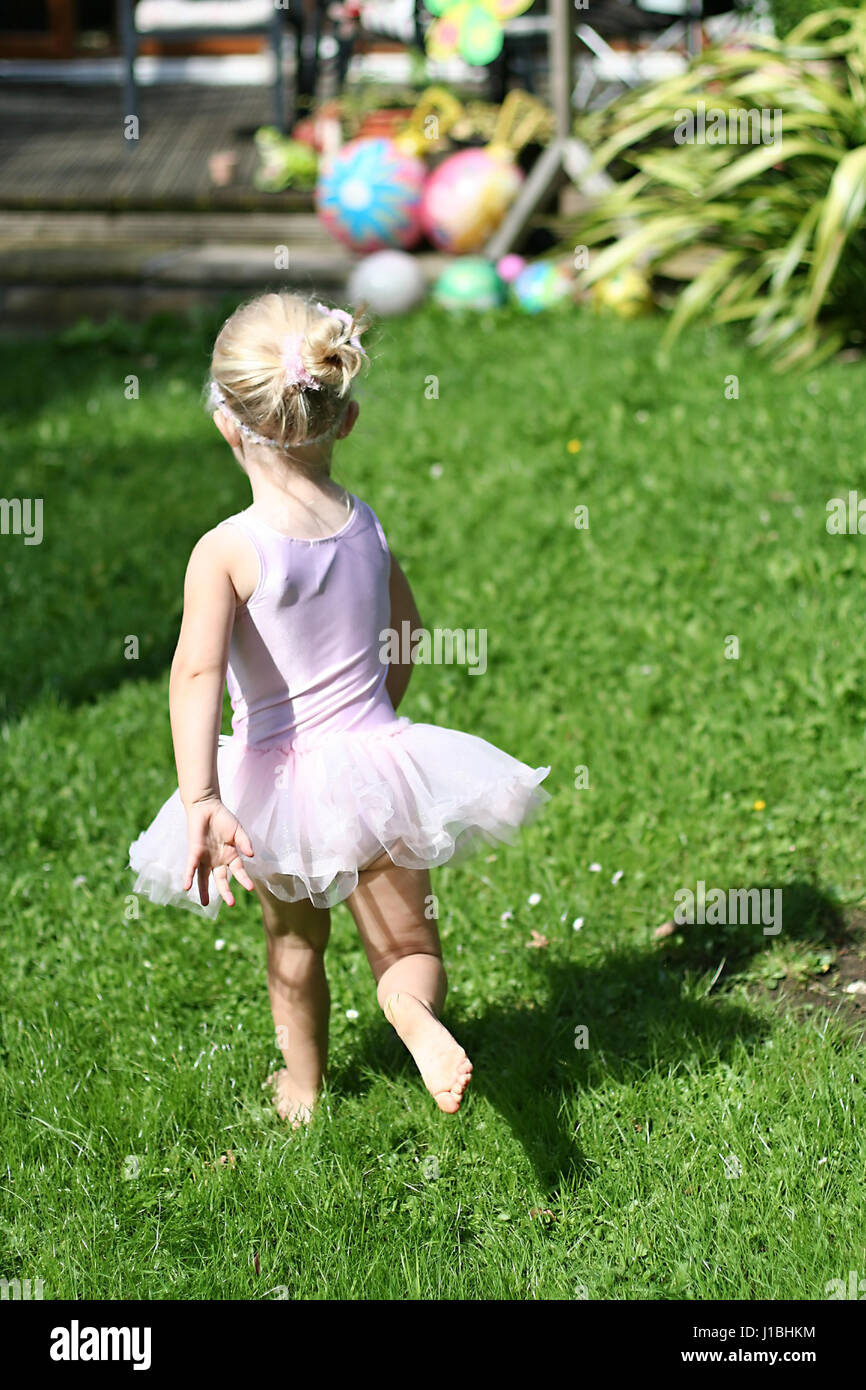 Little three year old girl, child playing with her annabel doll in the garden dressed in a tutu Stock Photo