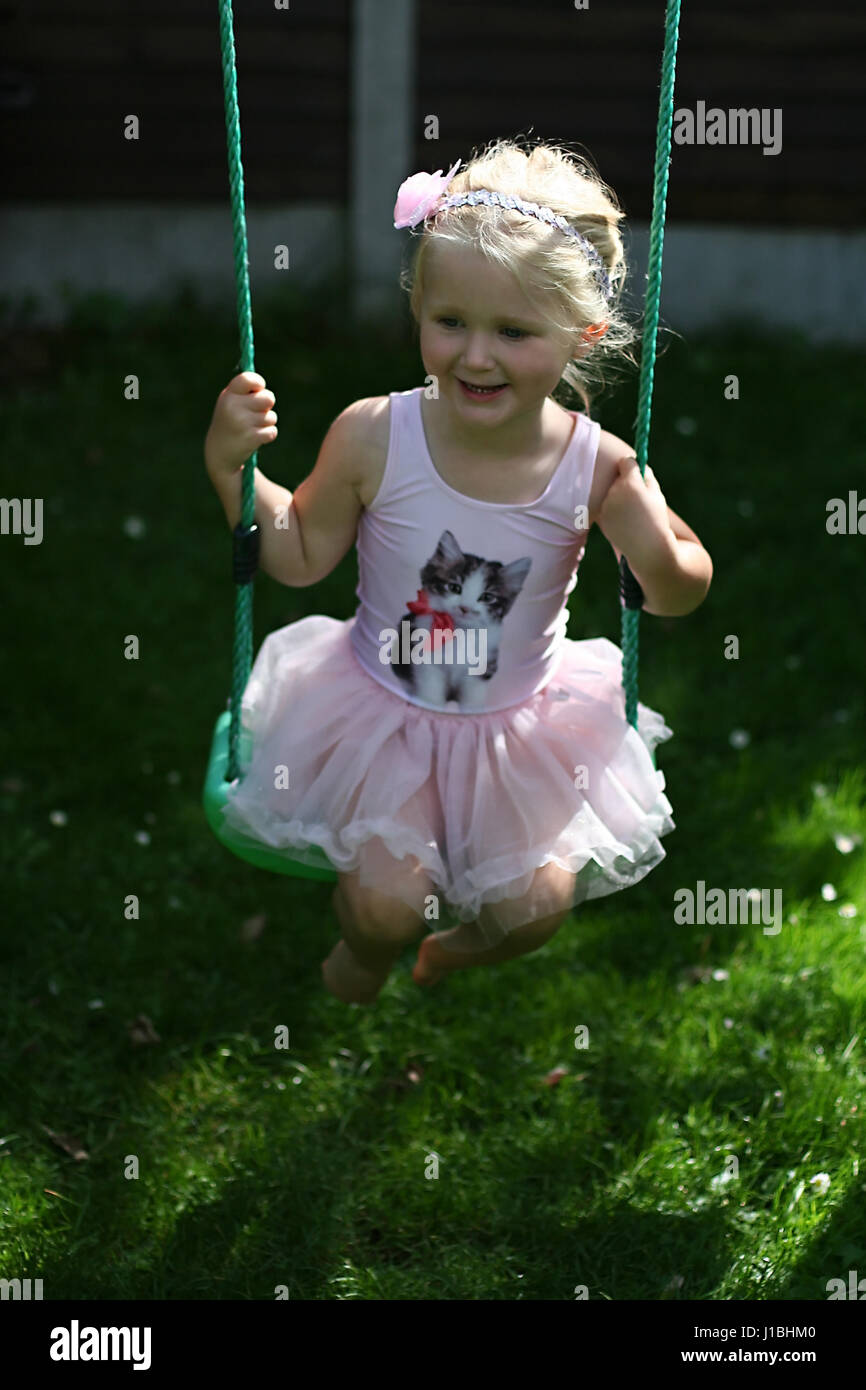 blonde child kid tutu swing swinging garden summer, childhood concept, freedom, carefree, happy times, time of her life, joy concept, happy Stock Photo