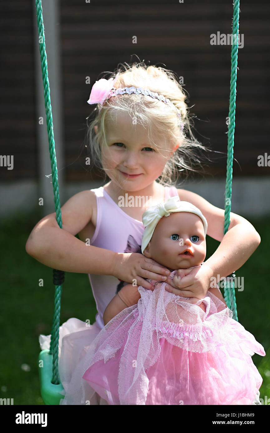 Little three year old girl, child playing with her annabel doll in the garden dressed in a tutu children toys Stock Photo