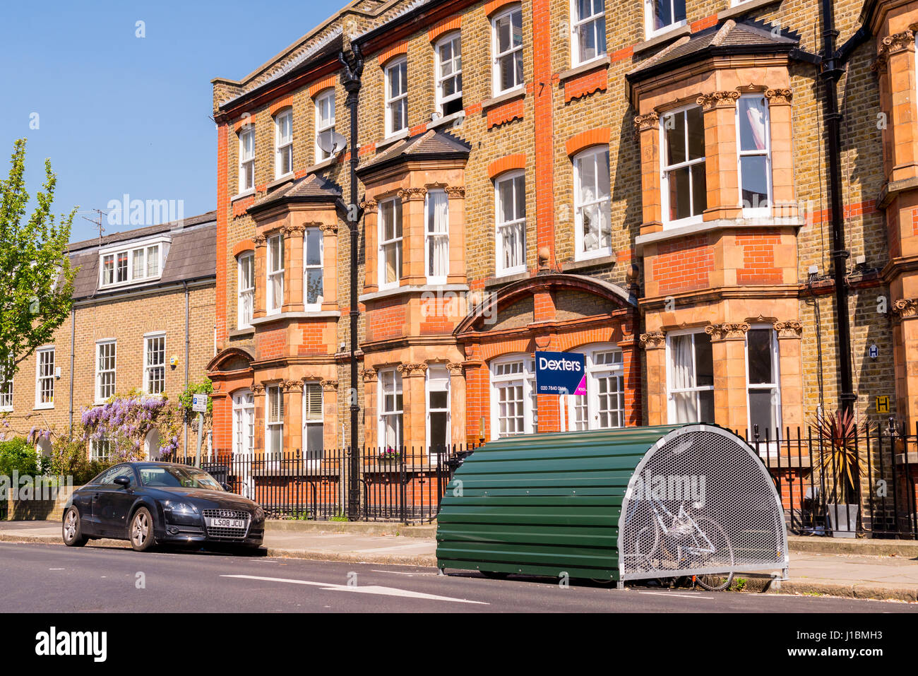 Classic British street with restored Victorian brick houses on a local road iin Lambeth with green bike shed next to the pavement. London, UK. Stock Photo