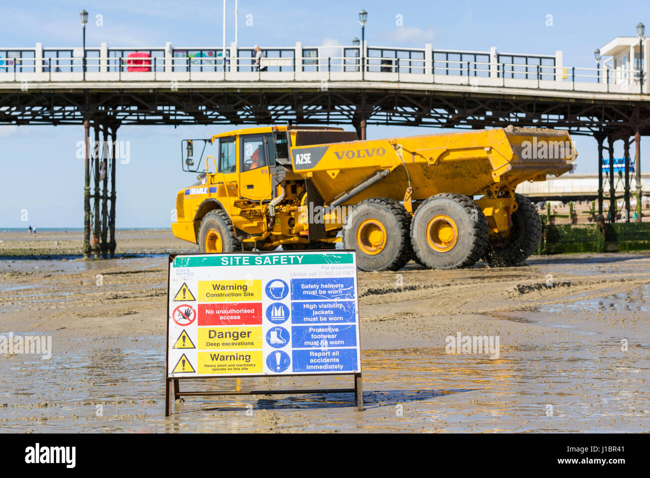 Site Safety sign at construction site on a beach. Volvo A25E Articulated Hauler moving shingle on Worthing Beach, Worthing, West Sussex, England, UK. Stock Photo