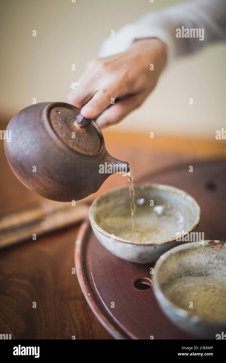 Sarah Hedden pouring tea into ceramic tea cups on a tray. Stock Photo