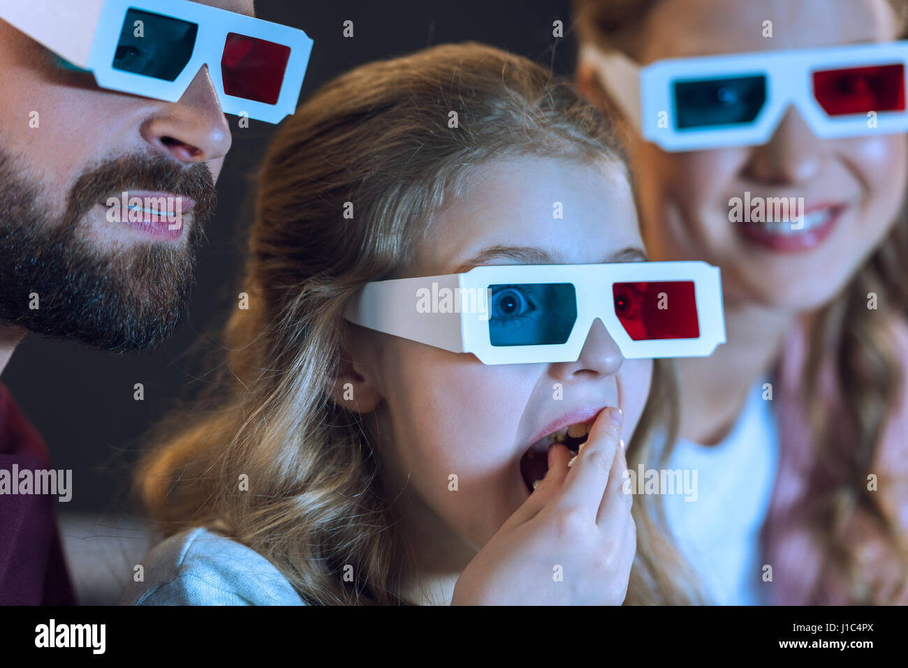 Closeup view of family wearing 3d glasses watching movie and eating