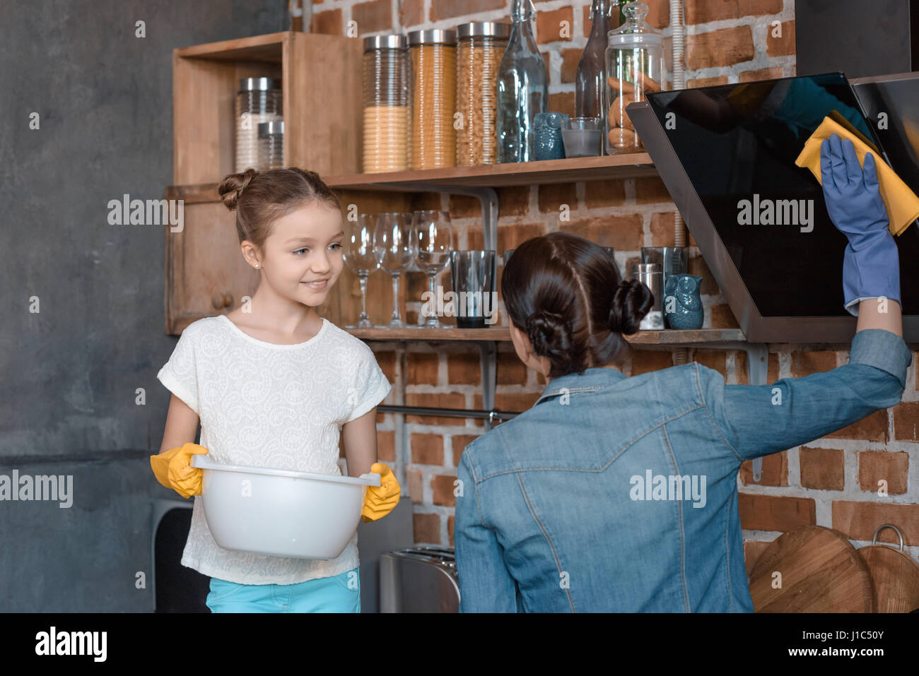 portrait of smiling daughter helping mother with housework at home Stock Photo