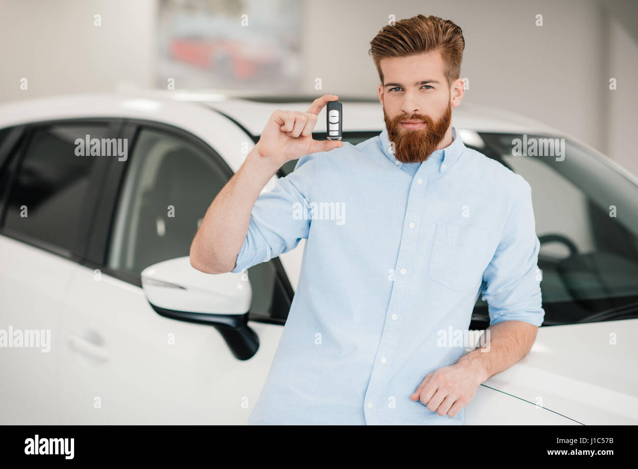 Man holding car key and standing at car in dealership salon Stock Photo ...