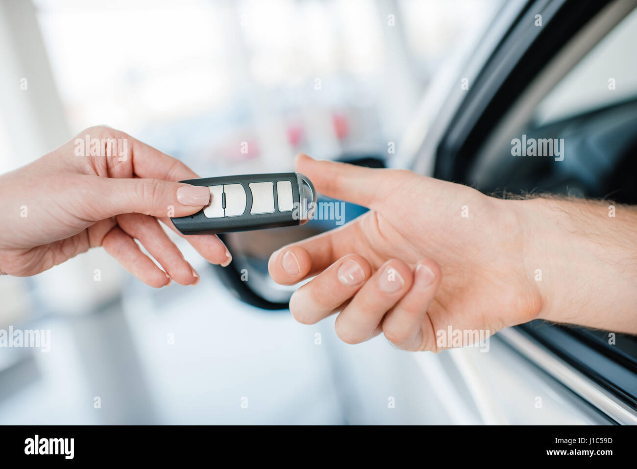 Close-up partial view of dealer giving car key to new owner Stock Photo ...
