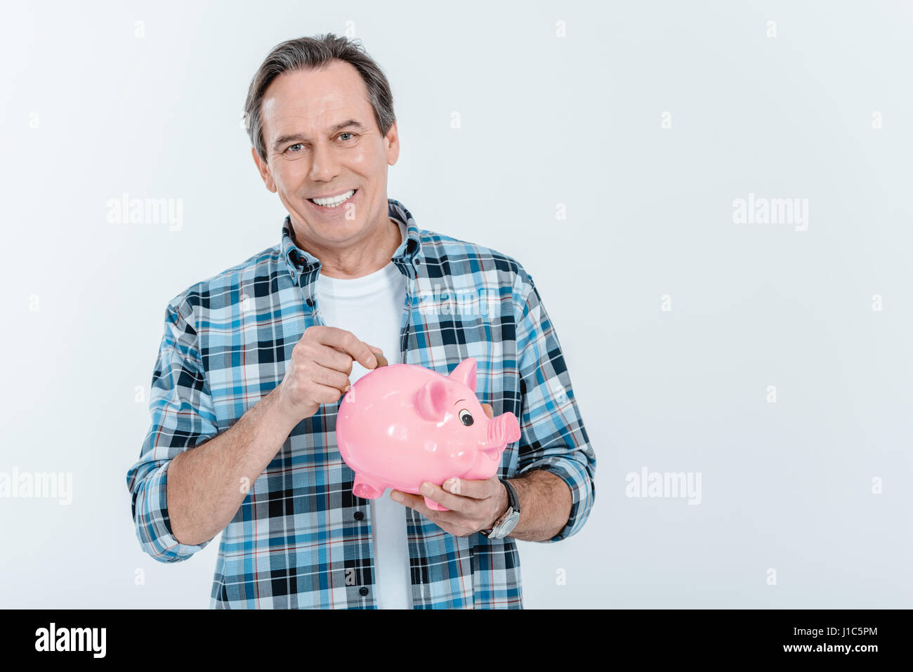 Front view of happy man putting coin in piggy bank on white Stock Photo ...