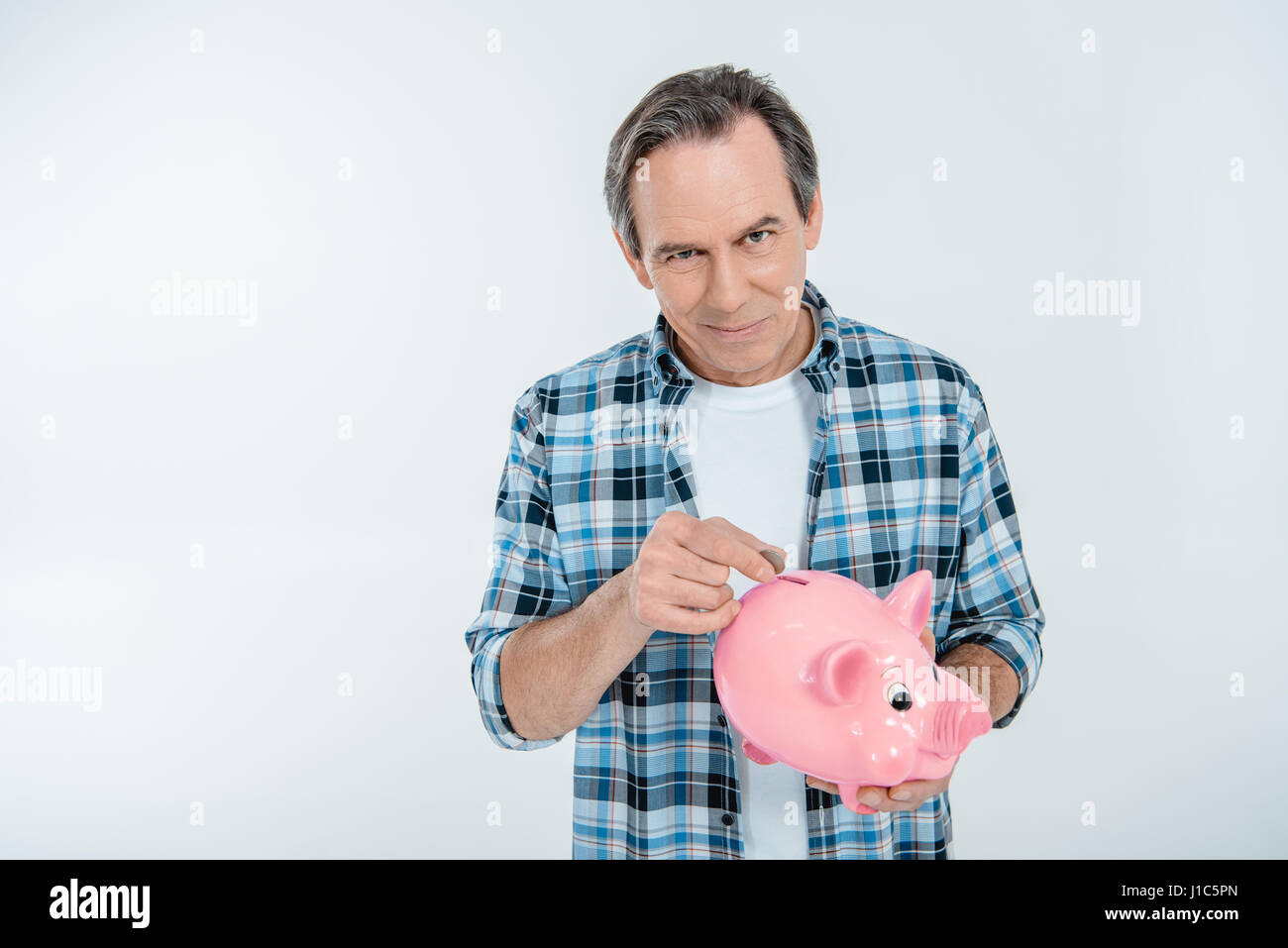 Front view of happy man putting coin in piggy bank on white Stock Photo ...