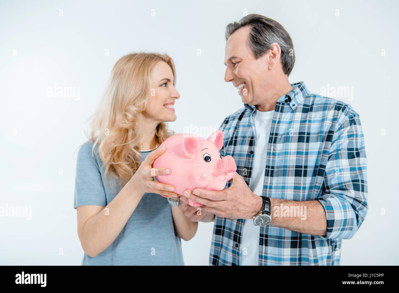 Front view of happy couple holding piggy bank on white Stock Photo - Alamy
